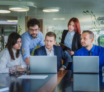 What types of insurance (IT department checking data on a laptop, meeting, modern office building)