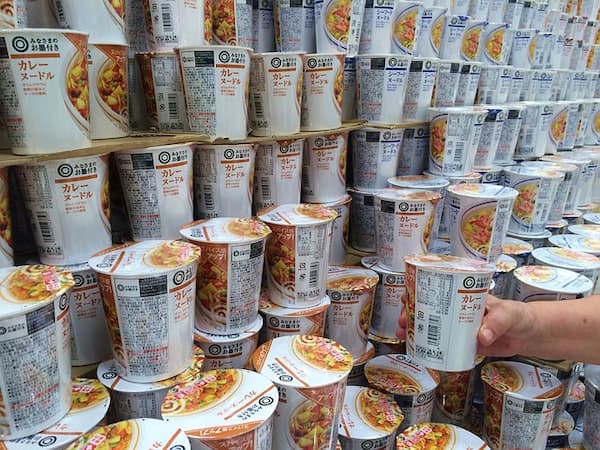 retragere produse alimentare - mana unui client tinand un ambalaj cu supa tip noodles de pe un raft de magazin