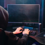 un hacker tasteaza la un computer cu linii de cod pe un ecran de monitor