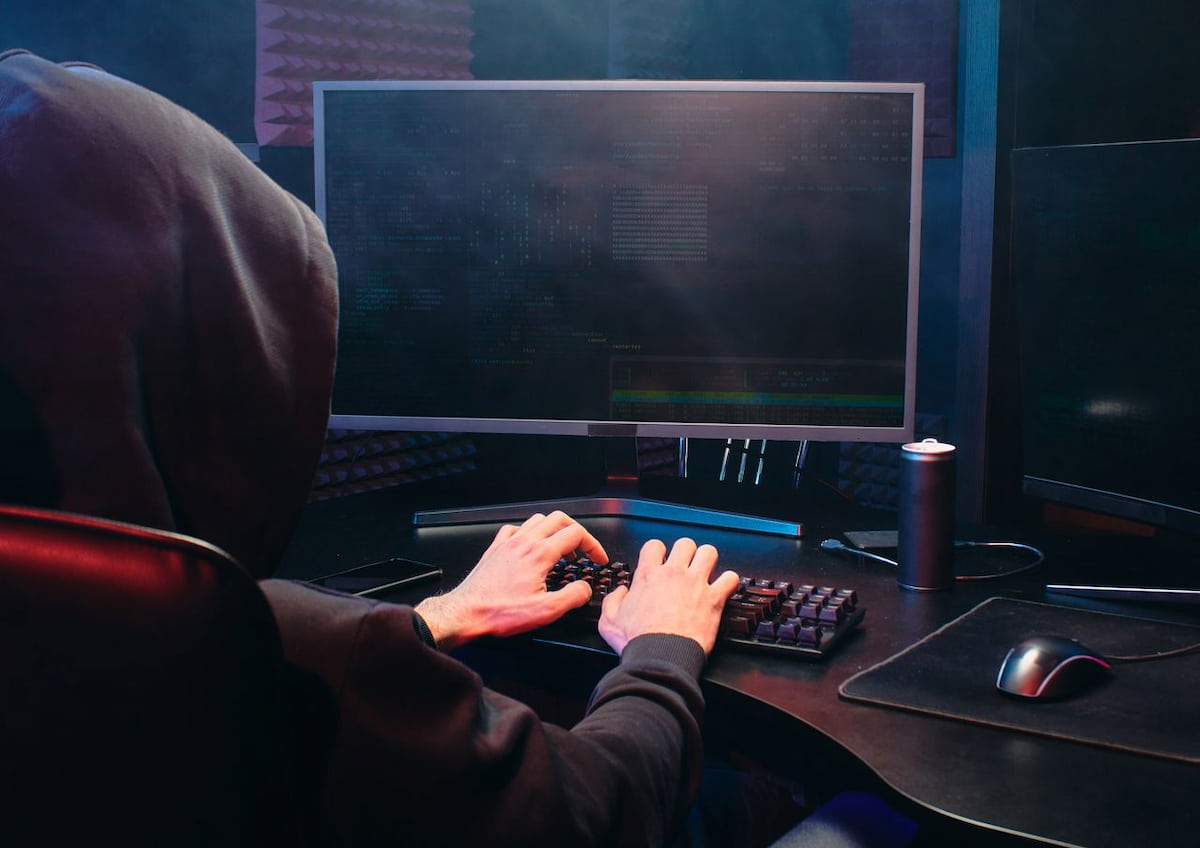 un hacker tasteaza la un computer cu linii de cod pe un ecran de monitor